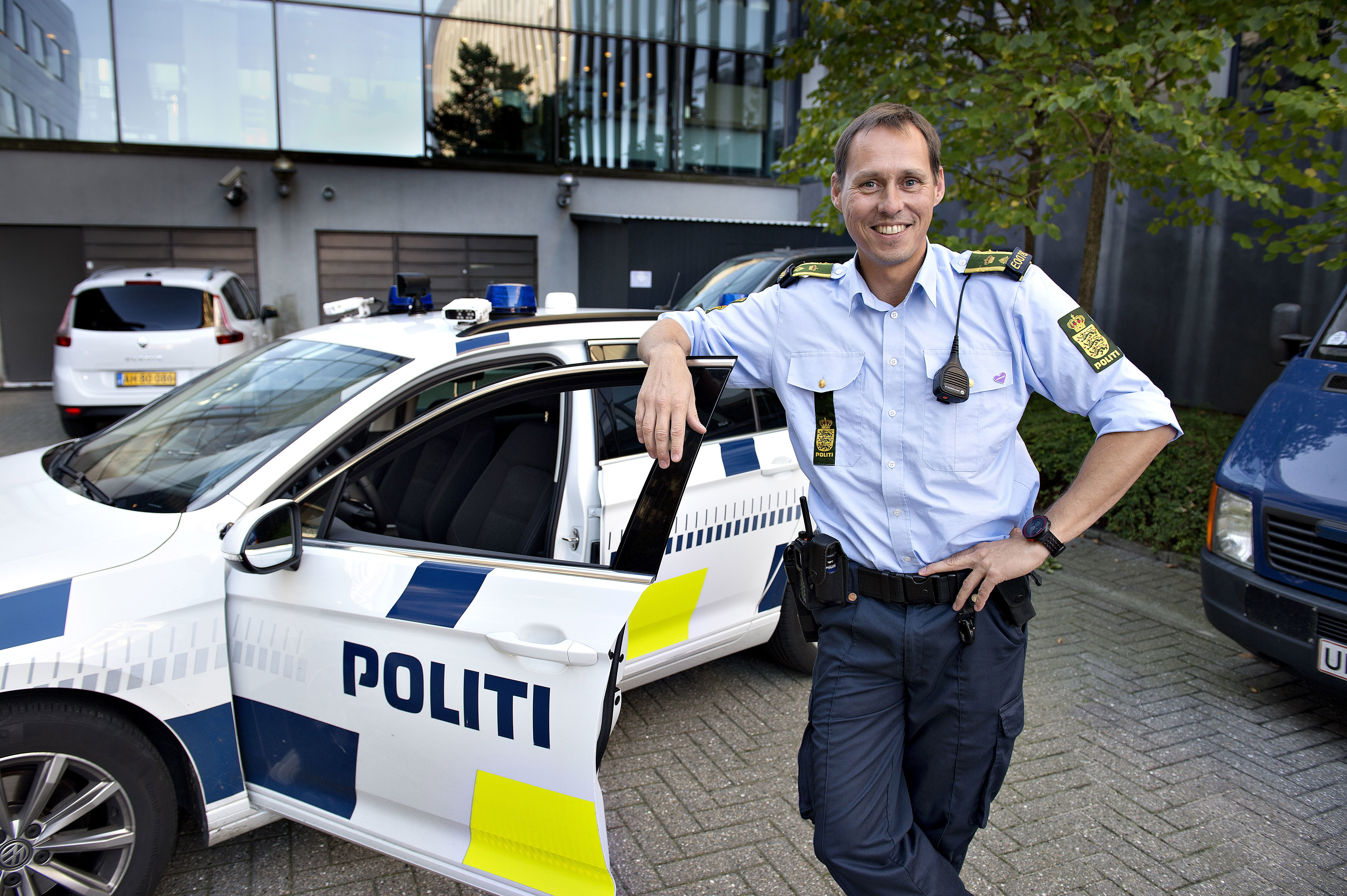 Politibetjent, der læner sig op af døren til politibil